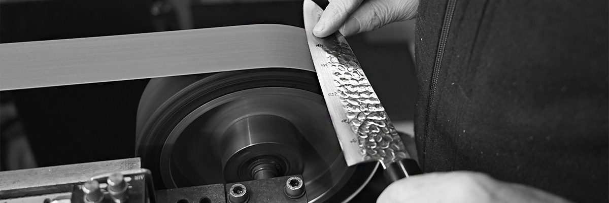 Knife on a belt grinder during dry sharpening